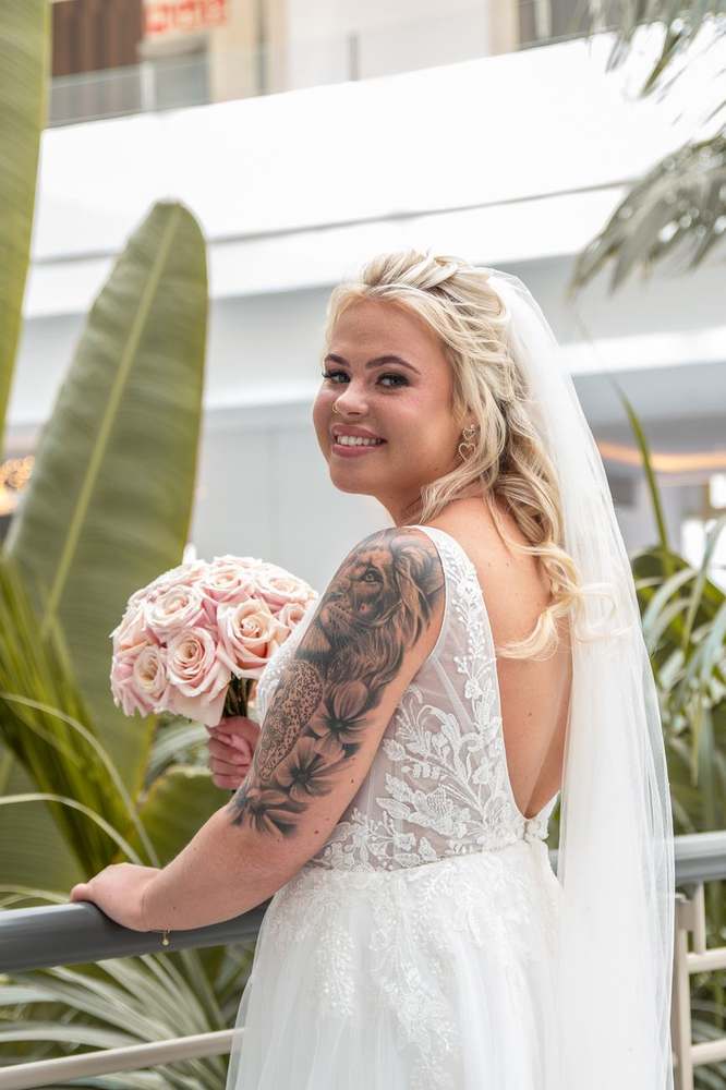Bruid met boeket kijkt lachend over haar schouder