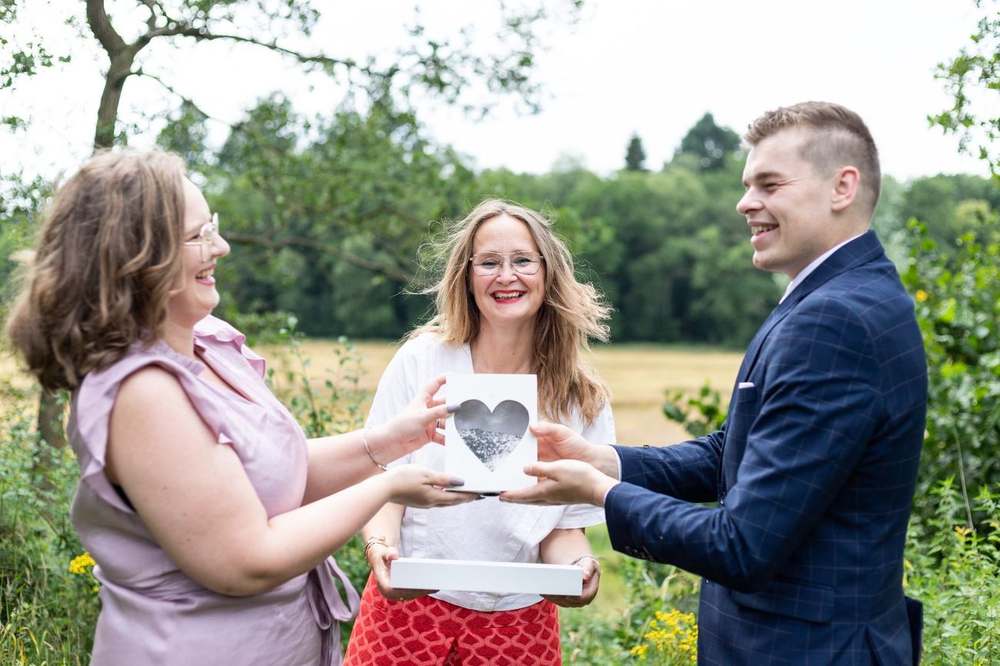 Bruidspaar en Lizette met de houten hartendoos tijdens de ceremonie in Nederland