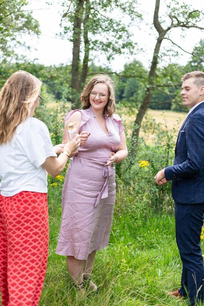 Lizette overhandigt een flesje tijdens de ceremonie in het veld